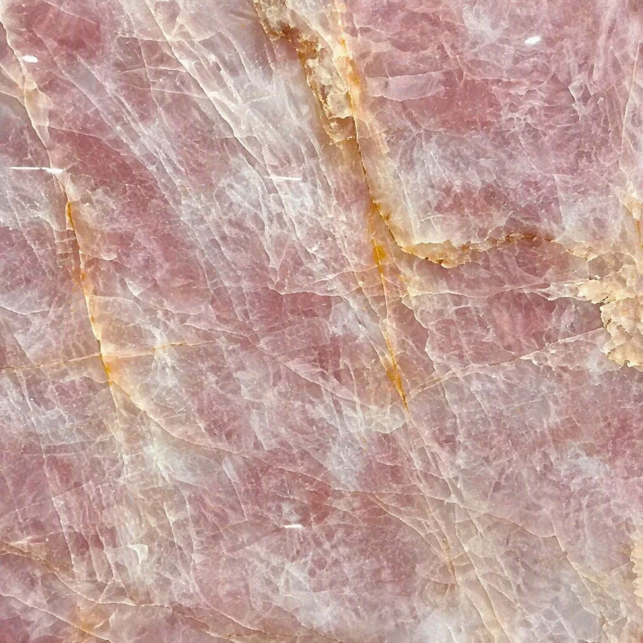 Close-up detail of Cristallo Pink quartzite featuring translucent pink crystals, soft white veining and natural golden mineral accents Close-up detail of Cristallo Pink quartzite featuring translucent pink crystals, soft white veining and natural golden mineral accents